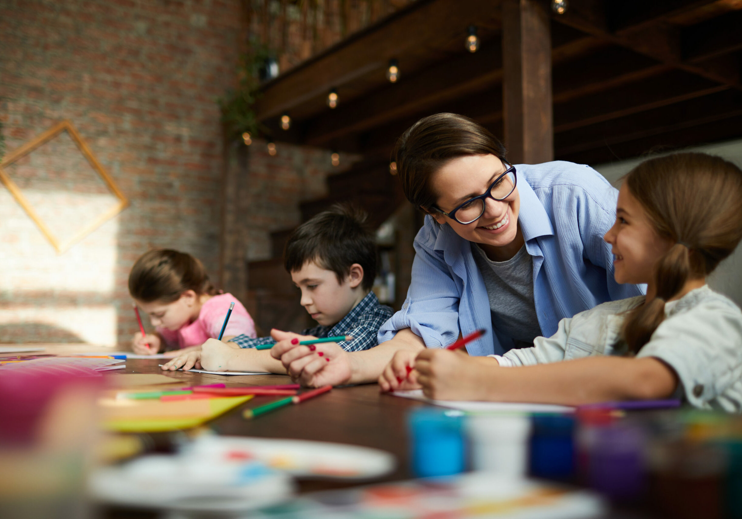 Portrait of smiling young woman working with kids in art class, copy space